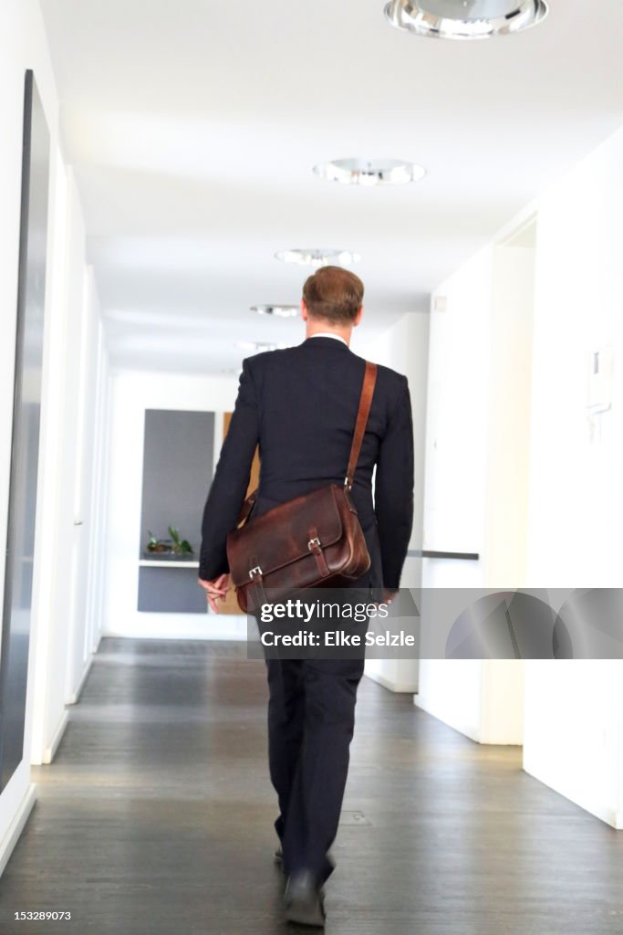 A business man with a bag walking in a corridor