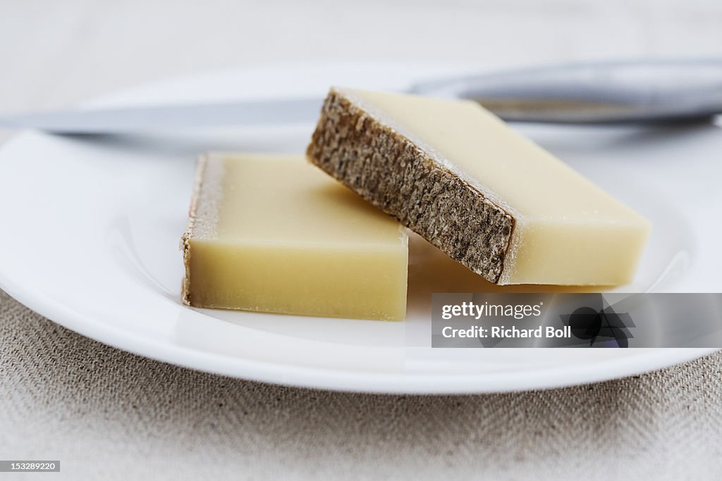 Two pieces of Gruyere cheese on a white plate