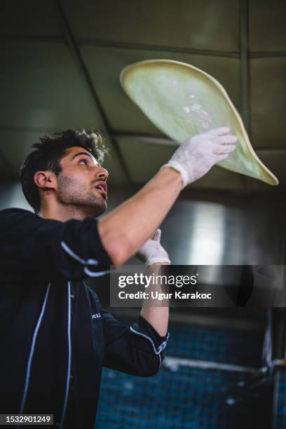 koch wirft pizzateig in der restaurantküche in die luft - pizza toss stock-fotos und bilder