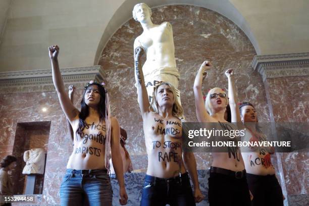 Topless activists of the Ukrainian women movement Femen shout slogans as they protest against anti women's politic in front of the Venus de Milo...