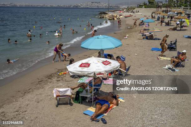 Beach goers are seen at Alimos beach near Athens, on July 15 as Greece is hit by a heat wave, like other several European countries. Parts of Greece...