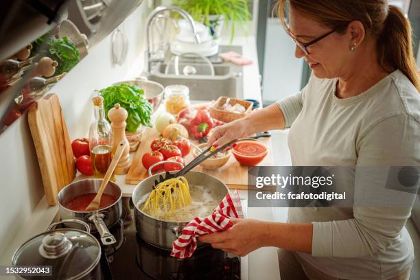 donna che cucina spaghetti fot ricetta italiana perfetta - bollente foto e immagini stock