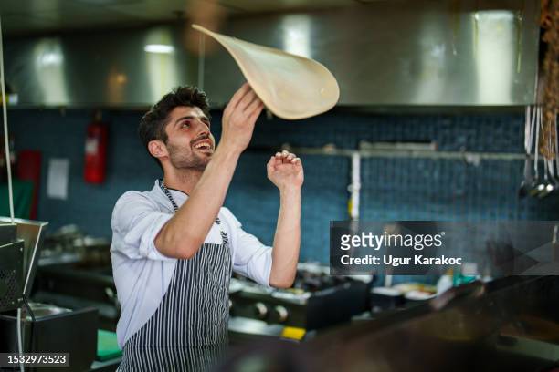 chef che prepara la pizza in cucina accanto al forno - pizza toss foto e immagini stock