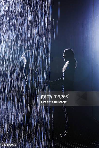 Members of the public experience the 'Rain Room' art installation by 'Random International' in The Curve at the Barbican Centre on October 3, 2012 in...