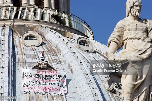 Marcello Di Finizio stands above a window ledge next to a banner displaying messages of protest against the Monti government and the Europe Union on...