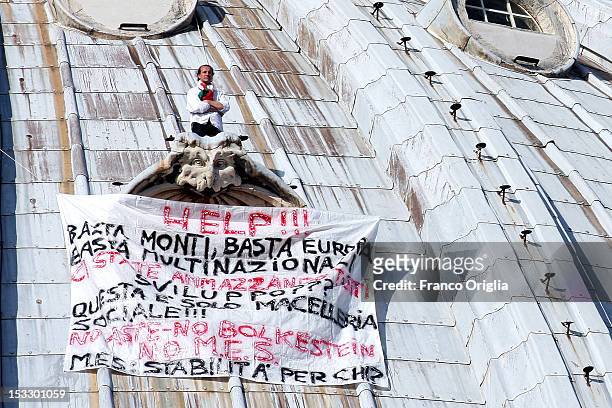Marcello Di Finizio stands above a window ledge next to a banner displaying messages of protest against the Monti government and the Europe Union on...