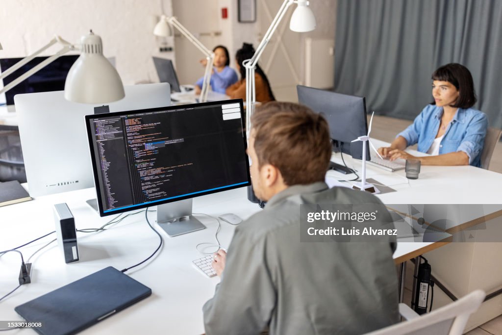 Software developer coding on computer and reviewing code for mistakes