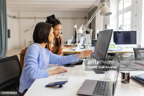 two software developers working together on an application coding at a coworking office - webdesigner stockfoto's en -beelden