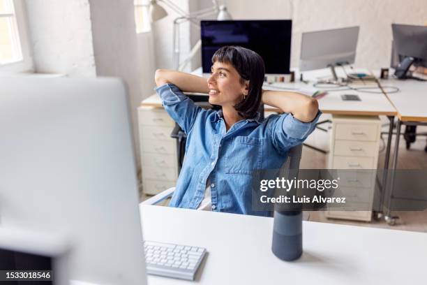 businesswoman taking a break from work at her office - silla oficina fotografías e imágenes de stock