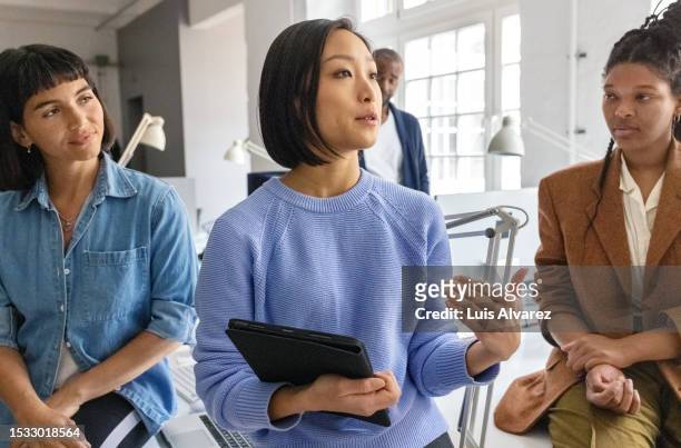 asian woman having meeting with group of colleagues at startup office - developer stock pictures, royalty-free photos & images