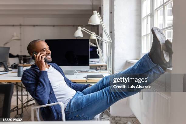 entrepreneur taking a break from work and talking on phone - feet up stock pictures, royalty-free photos & images