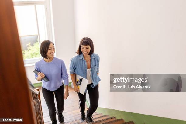 two women business partners walking up the stairs in office building and smiling - woman friends stock pictures, royalty-free photos & images