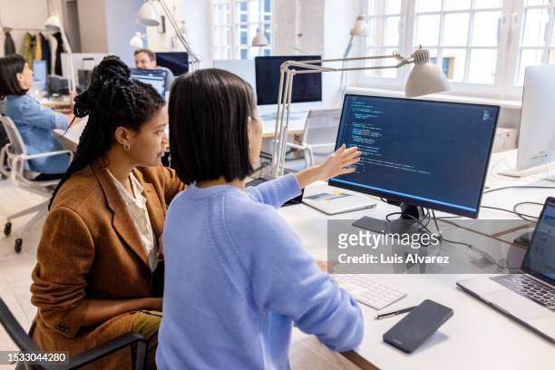 two software programmers working together at coworking desk using computer - women's short programme stock-fotos und bilder