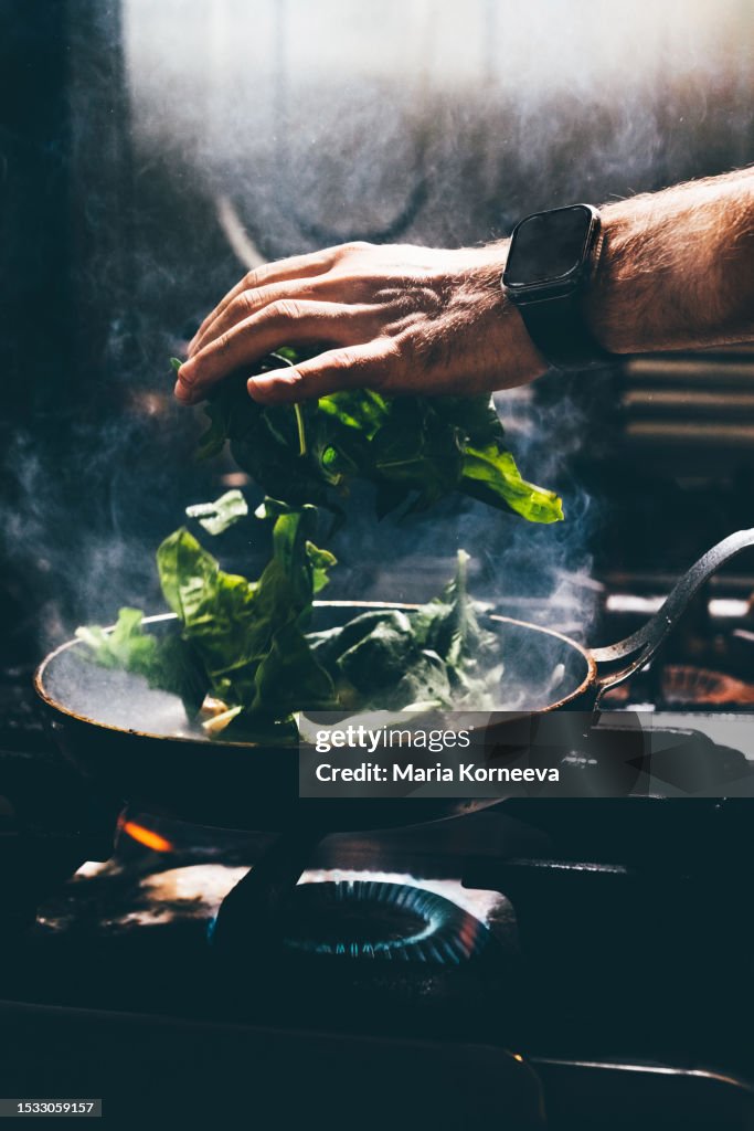 Chef frying vegetables in a pan.