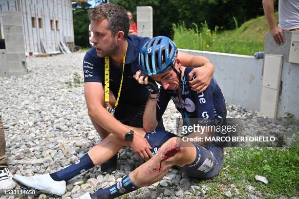 Team DSM - Firmenich's French rider Romain Bardet is assisted by a team member after crashing during the 14th stage of the 110th edition of the Tour...