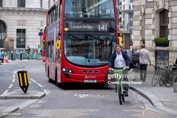 Cyclist in the City of London interacting with public transport buses on 6th July 2023 in London, United Kingdom. Cycling is a very popular mode of...