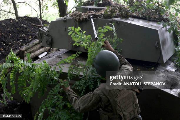 Ukrainian artilleryman uses tree branches to camouflage a military vehicle at the frontline near the town of Bakhmut, Donetsk region, on July 15 amid...