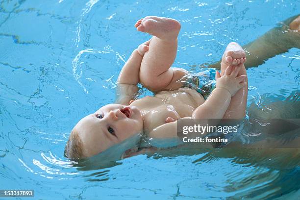 newborn baby swimming in pool - zwemmer stockfoto's en -beelden