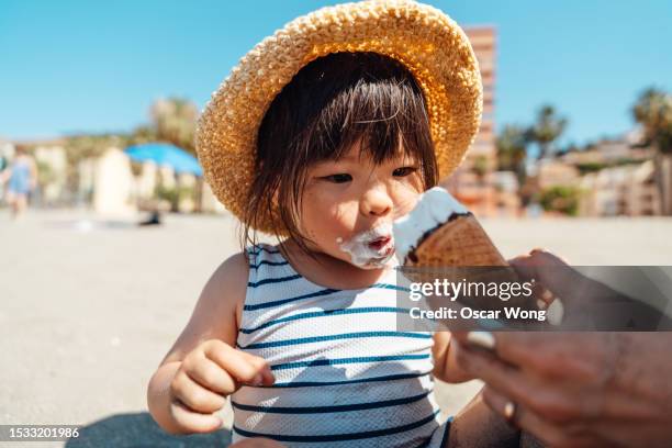 cheerful asian little girl feeling excited to have ice-cream on the beach - girl eating messy ice cream cone stock pictures, royalty-free photos & images
