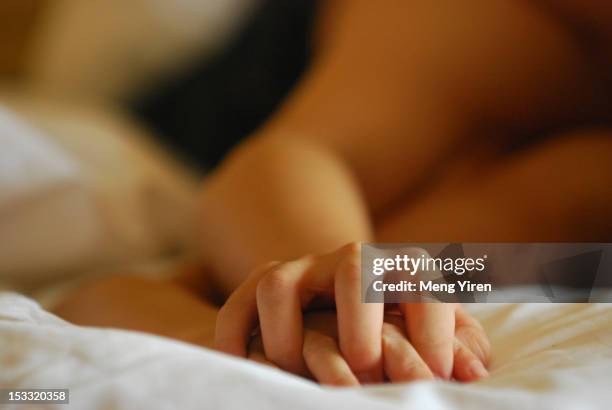 hand in hand - couple in bed ストックフォトと画像