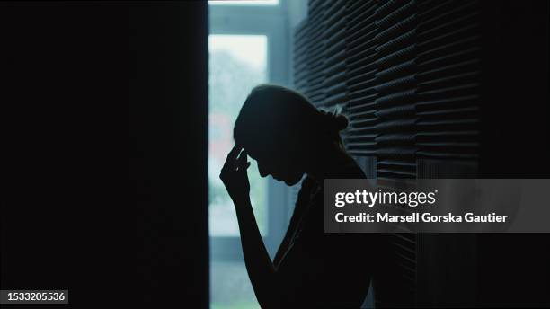 the girl sits in a dark room and suffers a mental breakdown - depression. - head in hands silhouette stock pictures, royalty-free photos & images