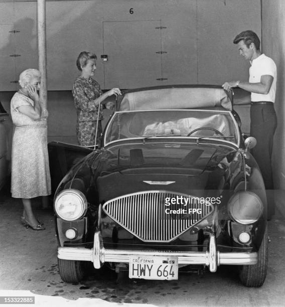 American actor Clint Eastwood and his first wife Maggie Johnson adjusting the roof of an Austin Healey sports car, Hollywood, California, circa 1960.