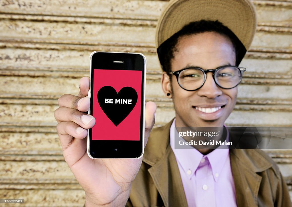 Yong man (glasses) showing a message on his phone.