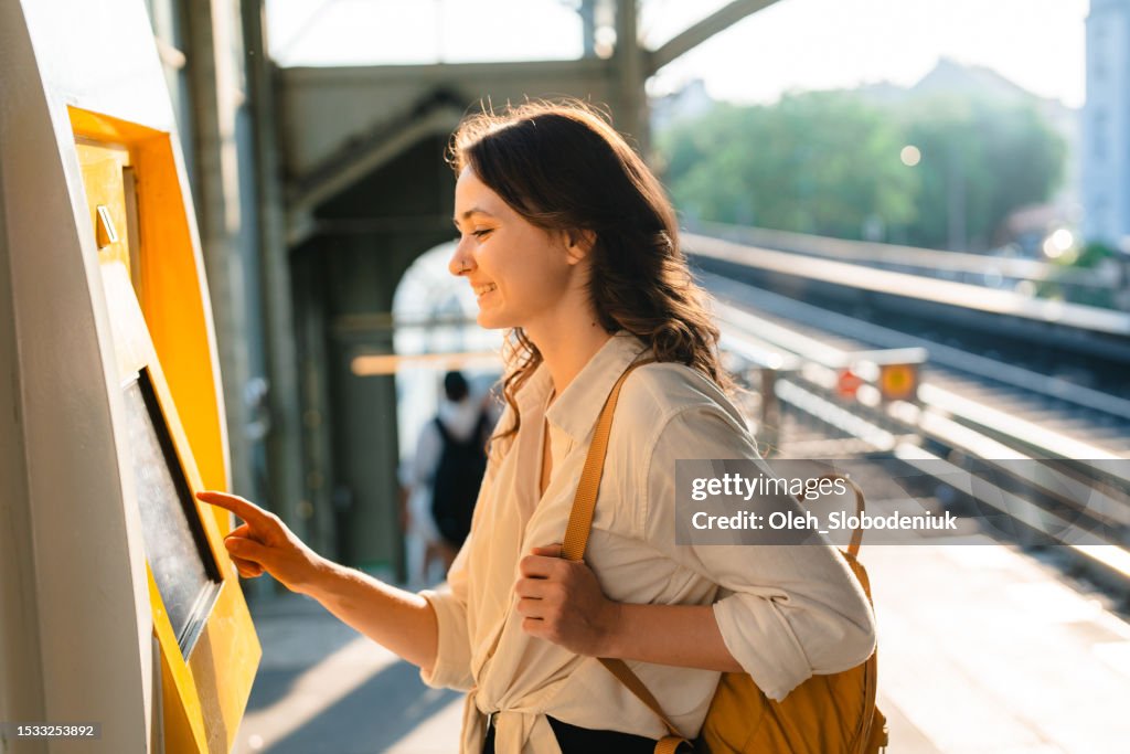 Frau kauft Fahrkarte am Fahrkartenautomaten am Bahnhof