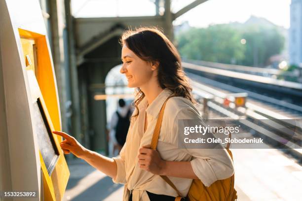 mujer comprando el billete en la máquina expendedora de billetes de la estación - tren de pasajeros fotografías e imágenes de stock