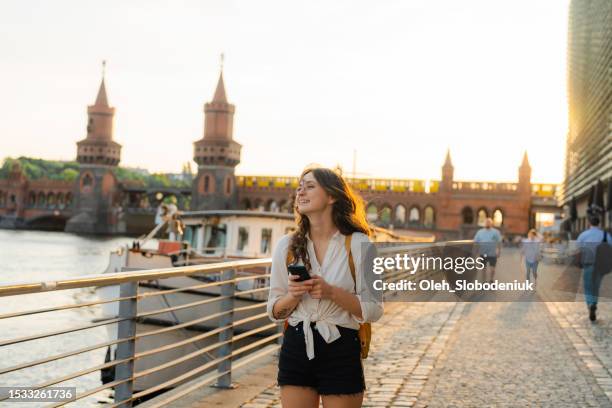 donna che usa lo smartphone mentre cammina a berlino - berlino foto e immagini stock