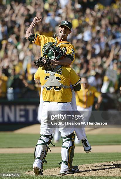 Pitcher Grant Balfour of the Oakland Athletics jumps into the arms of catcher Derek Norris celebrating defeating the Texas Rangers 12 to 5 and...