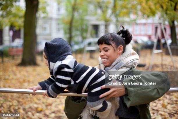 mum helping her baby to balance on a metal bar - monkey bars fotografías e imágenes de stock