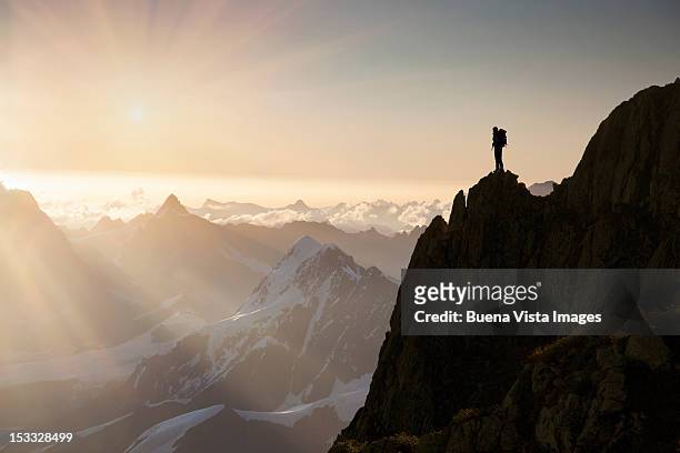 lone climber on top of a peak - ziel stock-fotos und bilder