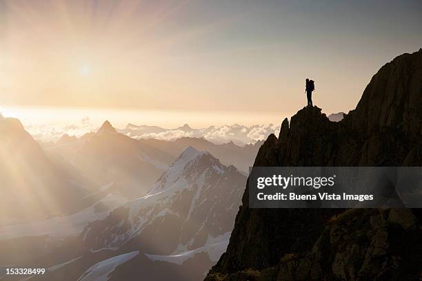 lone climber on top of a peak - person standing far stockfoto's en -beelden