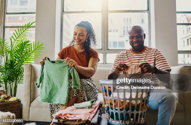 a husband and wife sits folding laundry. stock photo - afazeres domésticos imagens e fotografias de stock