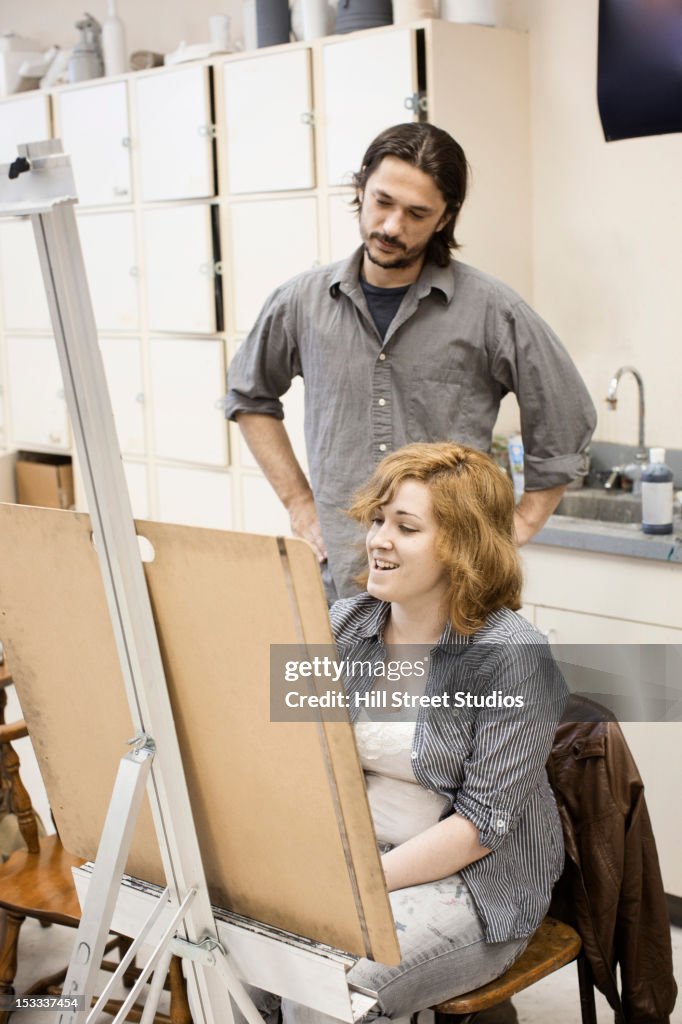 Teacher looking at students painting