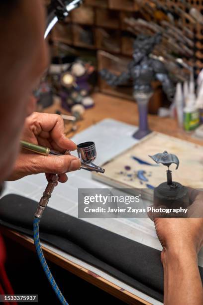 middle aged latin man painting 3d printed figure using an airbrush - airbrush stock-fotos und bilder