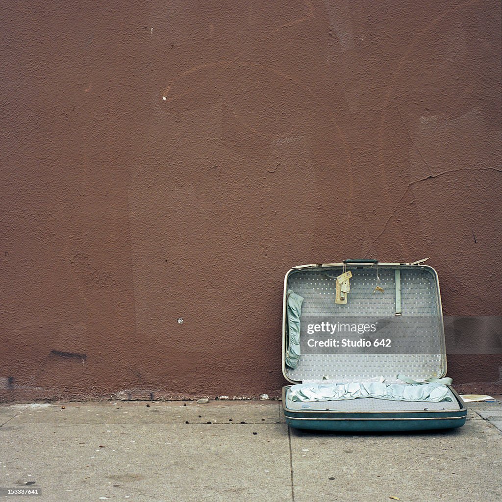 Discarded suitcase on sidewalk