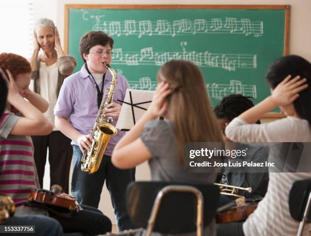 student playing saxophone badly - sad child and teacher stock pictures, royalty-free photos & images