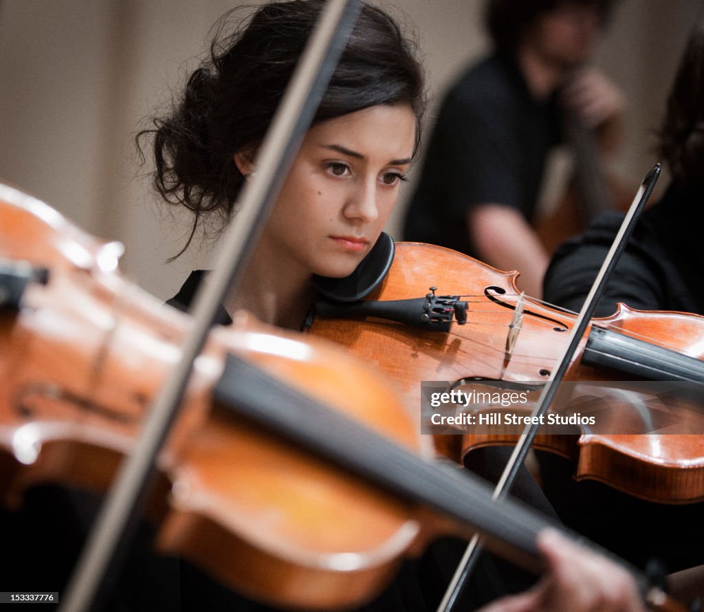 Woman playing violin in orchestra
