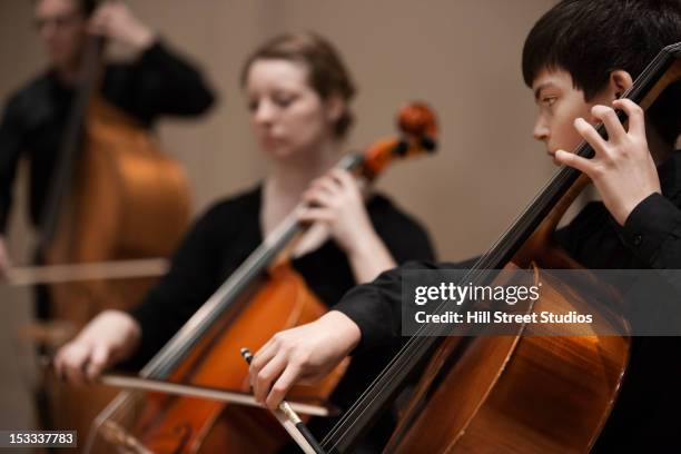 musicians playing cello in orchestra - kontrabass stock-fotos und bilder