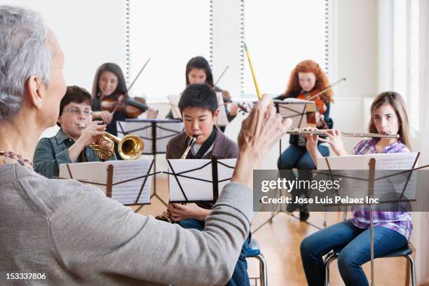 teacher instructing students in music class - kid conductor stock pictures, royalty-free photos & images