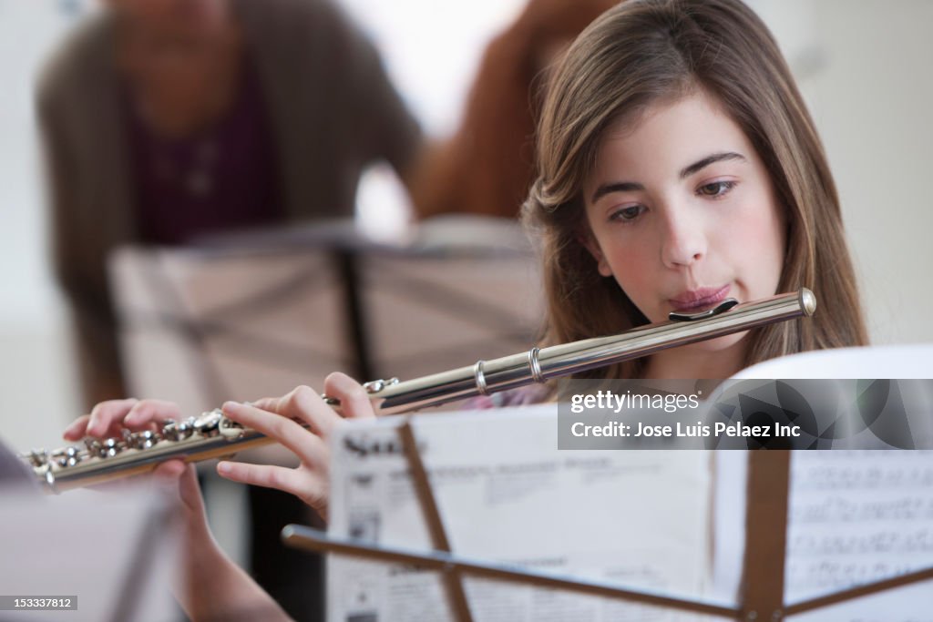 Caucasian student playing flute in music class