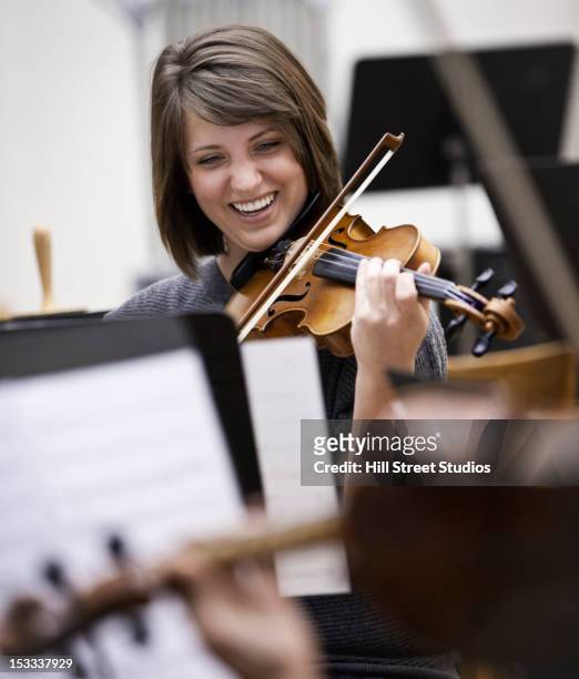 woman playing violin in orchestra - geiger stock-fotos und bilder