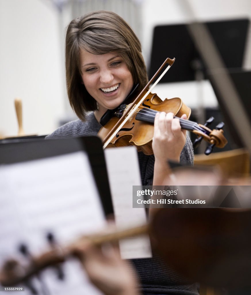 Woman playing violin in orchestra