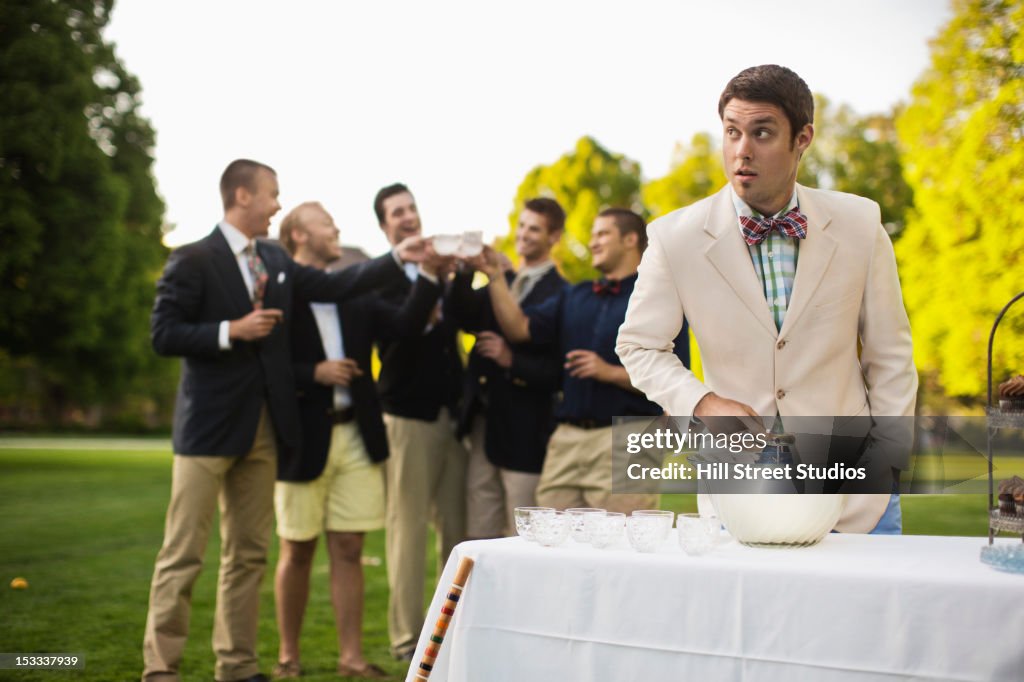 Man pouring alcohol into punch bowl