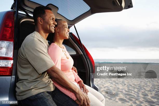 black couple sitting on hatchback enjoying the beach - holding hands in car stock pictures, royalty-free photos & images