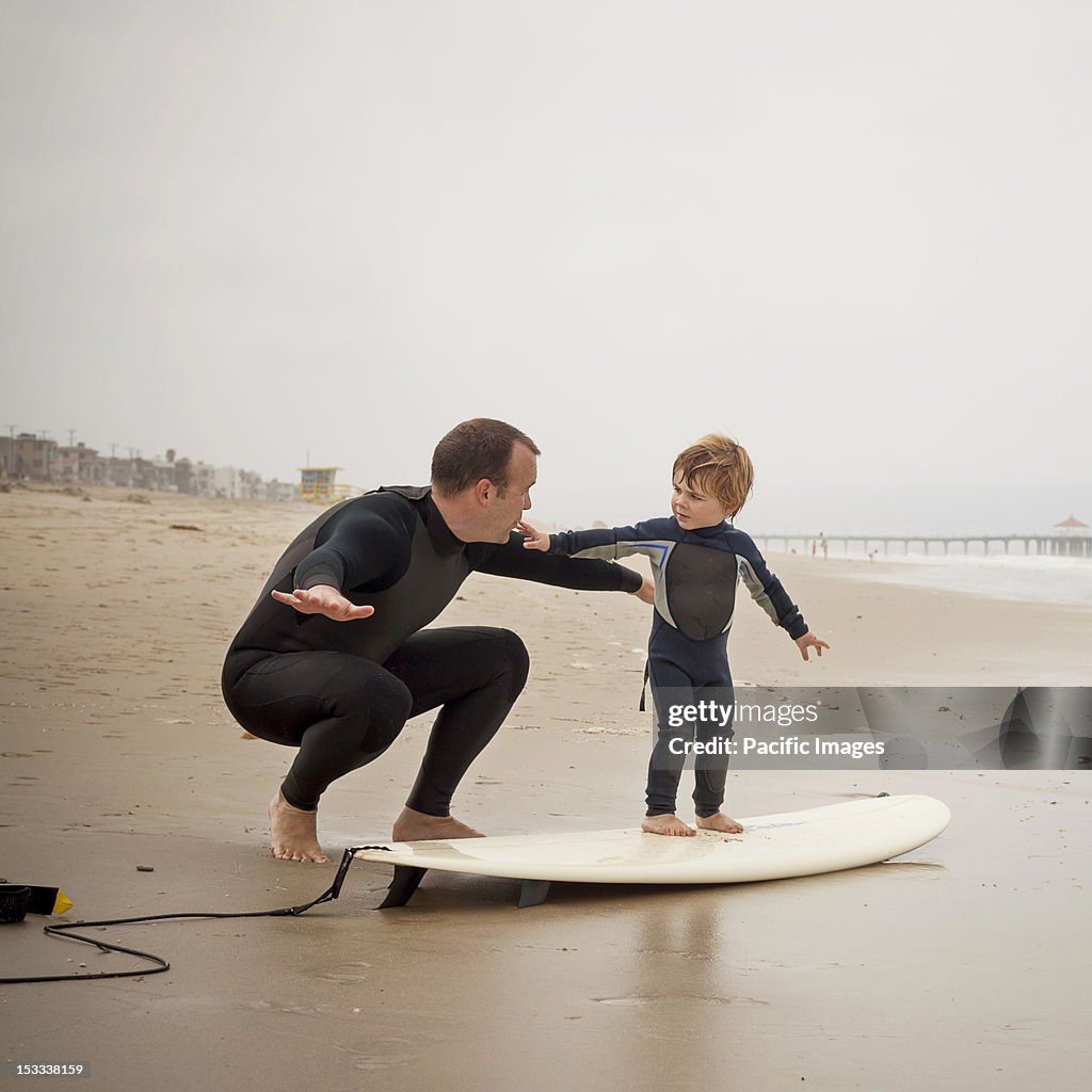 Caucasian father teaching son to surf