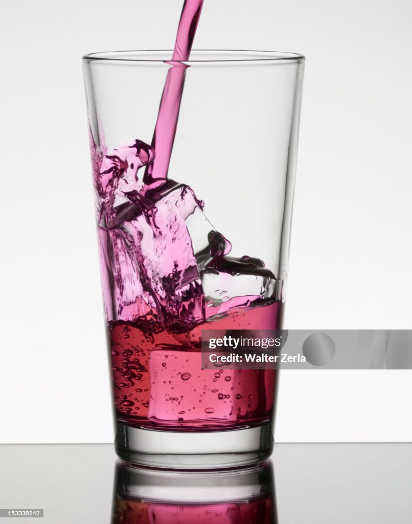 Pink liquid filling glass with ice