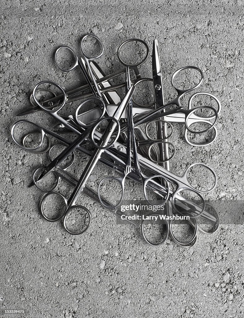 A pile of surgical scissors on cement